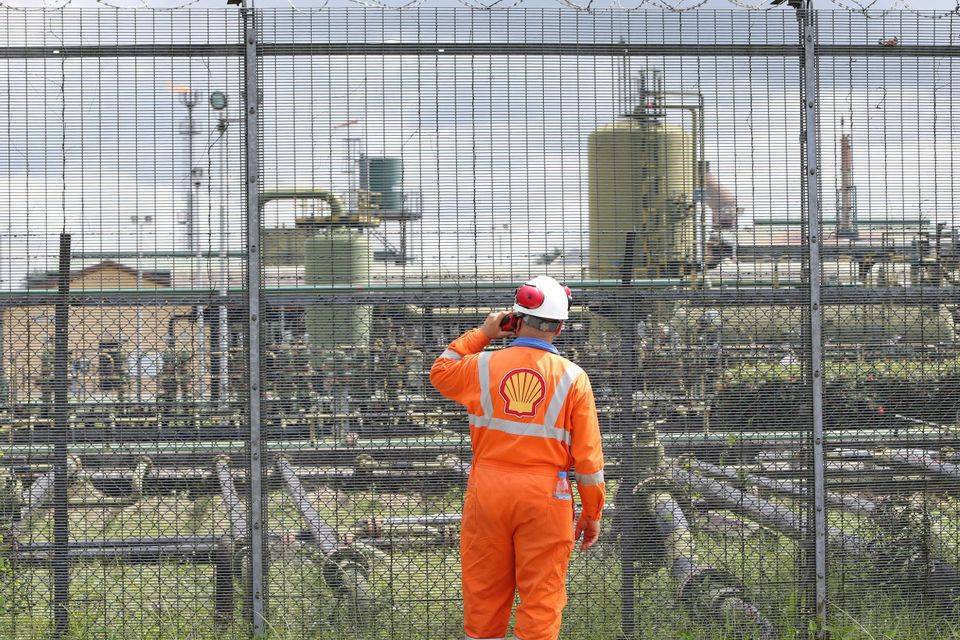 A worker is watching the facility operation conditions in the oil field enclosed by 358 high security fence.