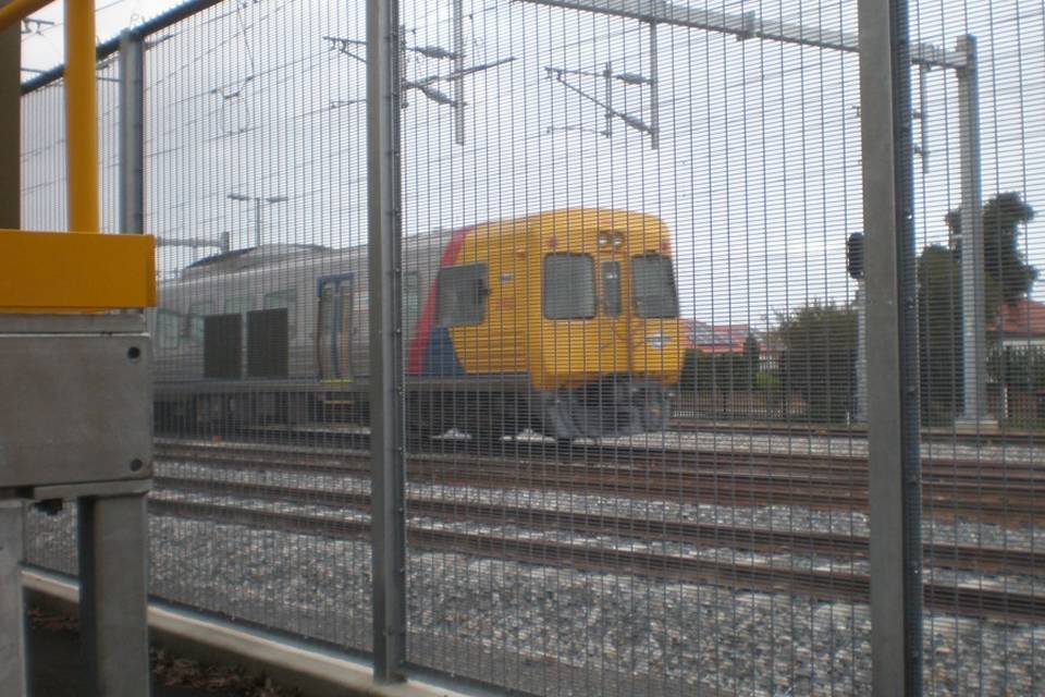 A train is running on the railway track enclosed by 358 high security fence.