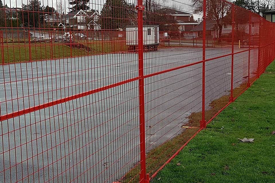A red Canada temporary fence is placed along the road for road construction.