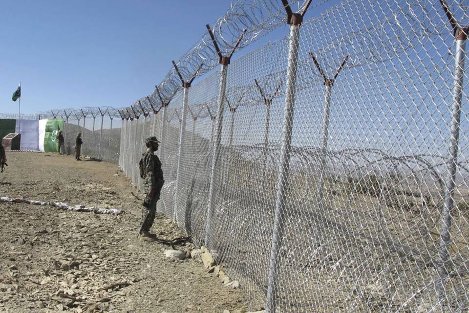 Los soldados están parados a lo largo de la cerca de alambre con una cobertura de concertina.