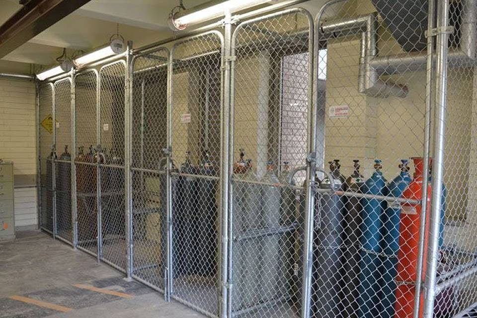 Several gas tanks are stored in partition fence made of chain link fence.