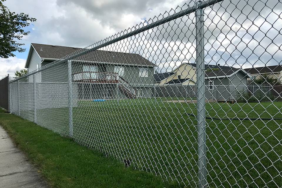 Several residential houses are enclosed by galvanized chain link fence.