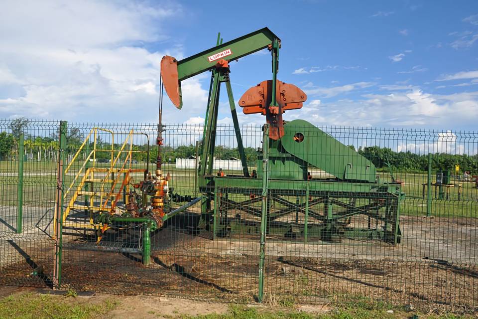 An oil developing machine is parked in the yard enclosed by curvy welded fence.