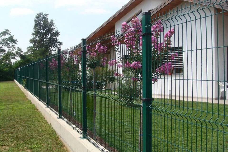 Flowers are planted in the yard encircled by curvy welded fence.